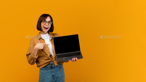 Wow, great website. Excited lady pointing at laptop with black screen, standing over yellow
