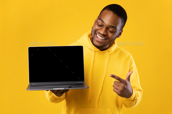Black Young Man Showing Laptop Blank Screen, Yellow Background, Mockup