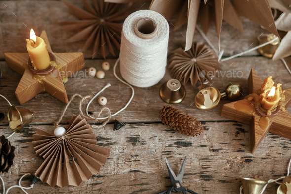 Stylish Christmas bells, paper angel, stars, pine cones, candle, thread and  scissors on rustic wood Stock Photo by Sonyachny