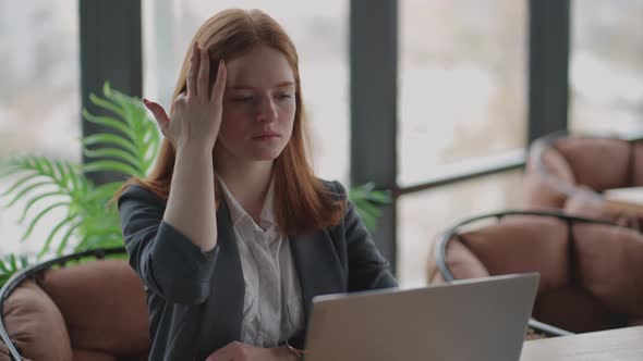 Thoughtful Concerned Redheaded Woman Working on Laptop Computer Looking Away Thinking Solving alt