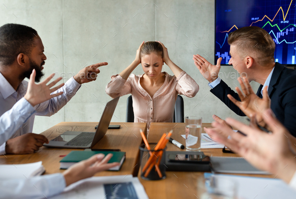 Angry Male Coworkers Shouting At Stressed Female Colleague At Meeting In Office
