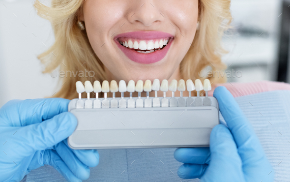 Dentist applying sample from tooth scale to patient white teeth