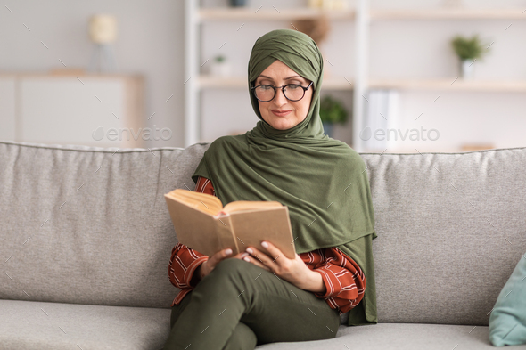 Happy Senior Islamic Lady Reading Book Wearing Glasses At Home Stock ...