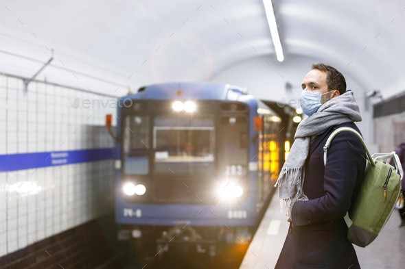 Man passenger wear face mask waiting train at subway station. Flu, covid in public transportation
