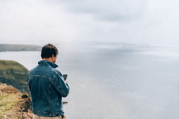 Man is standing on edge of the cliff on Irish sea