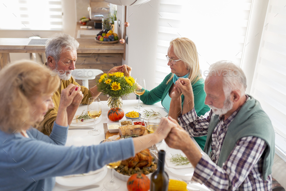 Senior people praying before Thanksgiving dinner