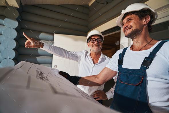 Smiling builders estimating the amount of work with layout - Stock Photo - Images