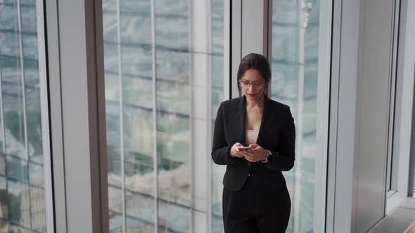 Portrait of a Young Modern Business Woman on the Background of Buildings of Glass and Metal alt