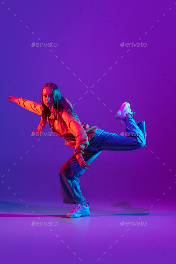 Stylish sportive girl dancing hip-hop in stylish clothes on colorful  background at dance hall in Stock Photo by master1305