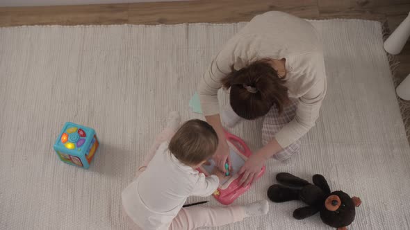 Happy Family Mother Teaching Cute Child Girl Playing on Warm Floor at Home alt