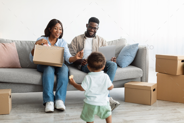 Happy family using laptop playing with kid after relocation - Stock Photo - Images