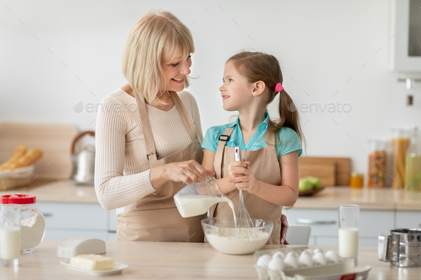 Happy mature lady and her granddaughter kneading dough - Stock Photo - Images