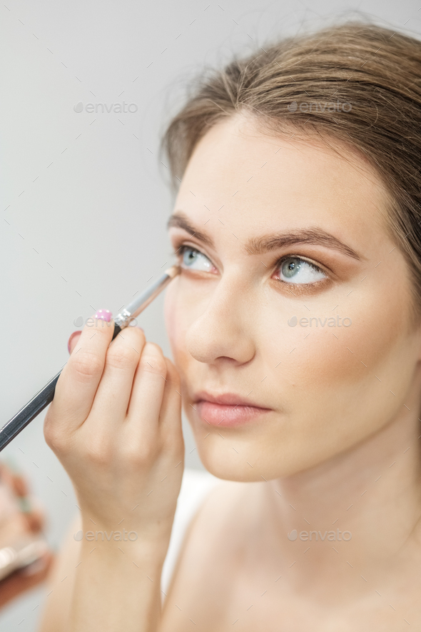 Makeup artist applies eye shadow . Beautiful woman with make-up