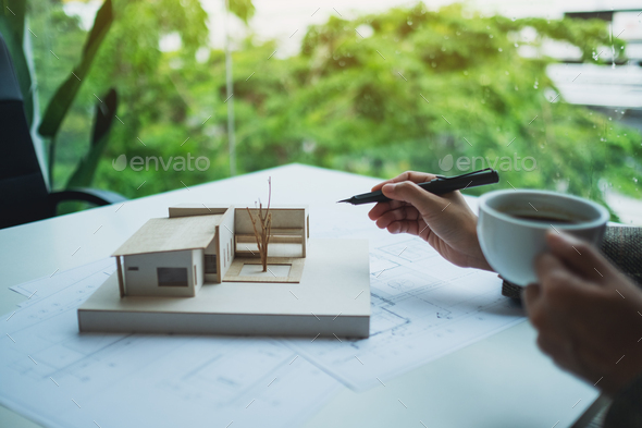 An architect working on an architecture house model with shop drawing paper in the office