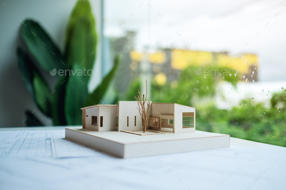 An architecture model with shop drawing paper on table in office with blur nature background