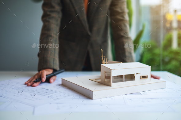 A female architect working on an architecture house model with shop drawing paper in the office