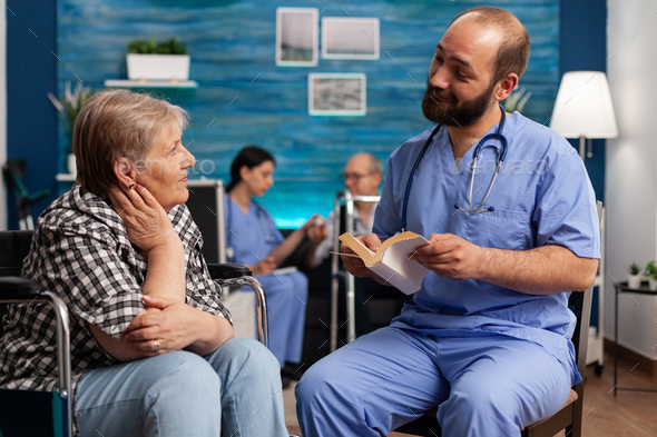 Caregiver support nurse reading book stories to senior disabled pensioner