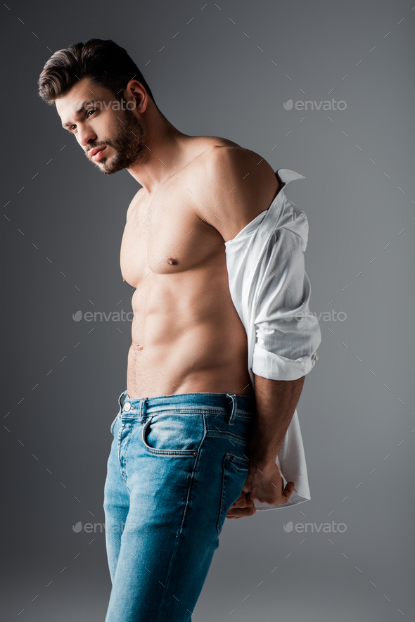 seductive muscular man in white shirt and jeans on grey Stock Photo by ...