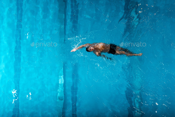 top view of handsome swimmer doing backstroke swimming in swimming pool