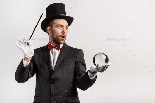shocked magician holding wand and magic ball, isolated on grey Stock ...