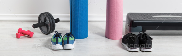 panoramic shot of yoga mats, sneakers, step platform and sport equipment on floor at home