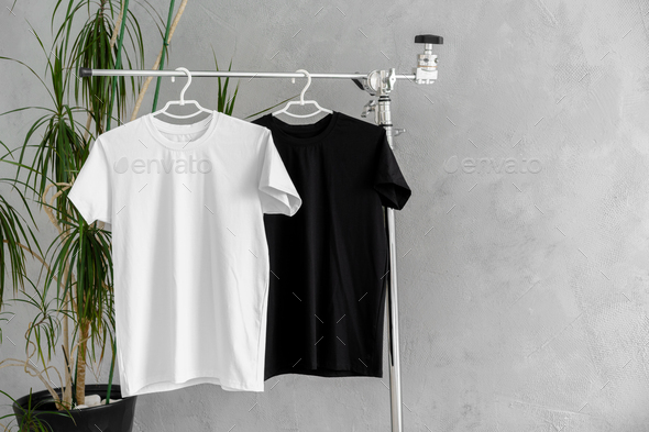 Row of black and white t-shirts hanging on rack Stock Photo by FabrikaPhoto