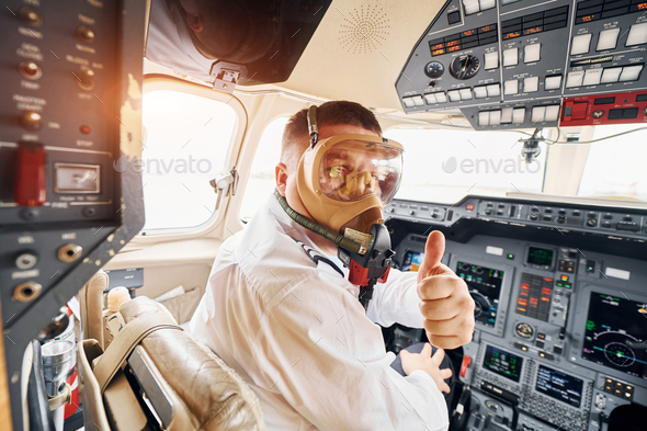 In oxygen mask. Pilot in formal wear sits in the cockpit and controls airplane