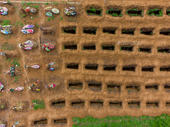 Open empty graves among the green lawn, aerial drone view of emty tombs.