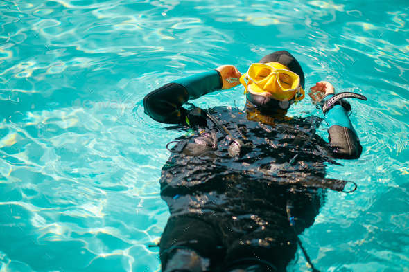 Female diver in scuba gear poses in pool, top view