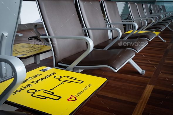 Yellow social distance sign on terminal chairs at airport. Safety measures from covid-19 pandemic