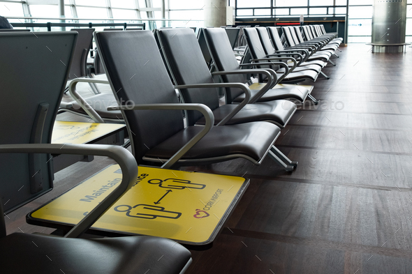 Yellow social distance sign on terminal chairs at airport. Safety measures from covid-19 pandemic