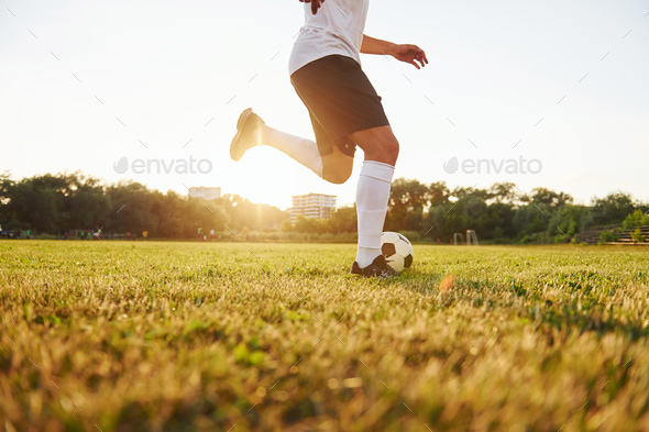 Runs with ball. Young soccer player have training on the sportive field