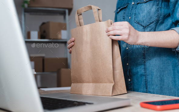 Young woman preparing drop shipping package for fast deliver inside small warehouse business