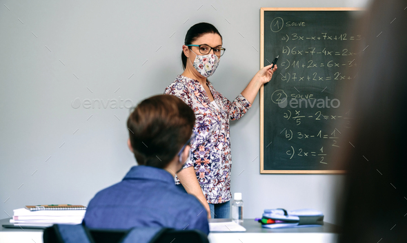 Teacher with mask in math class with student raising hand