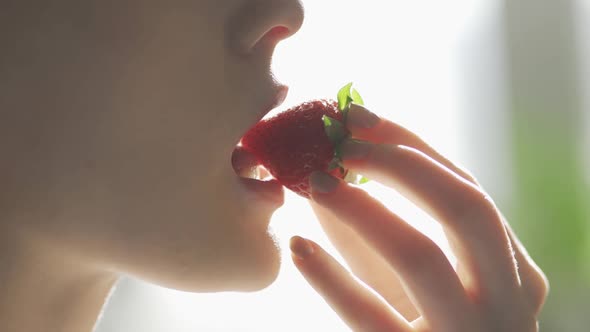 Young Woman Eating Ripe Strawberries Closeup alt