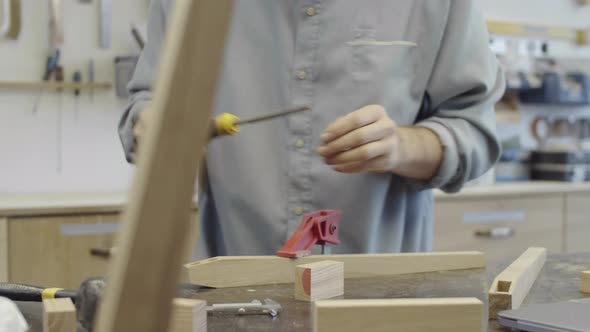 Carpenter Chiseling Slot in Wooden Element and Measuring with Calipers alt