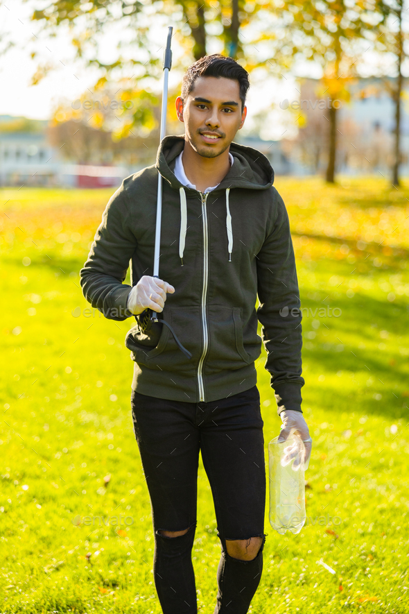 Confident and responsible volunteer cleaning park for trash on sunny day - Stock Photo - Images