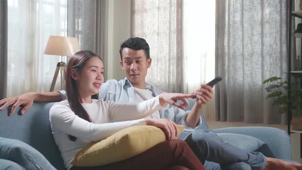 Young Asian Couple Relaxing And Watching Tv At Home alt