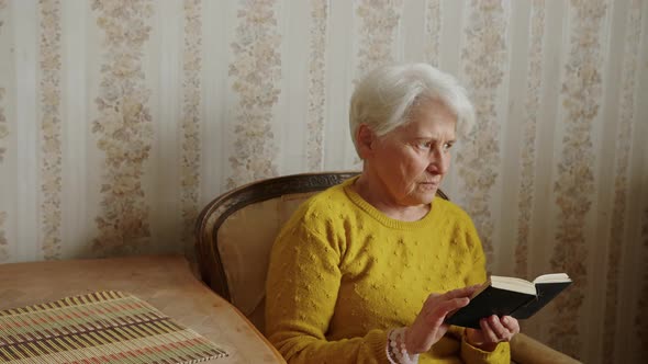 Senior Caucasian Woman Holding the Bible and Pondering Medium Shot Living Room Religion and alt