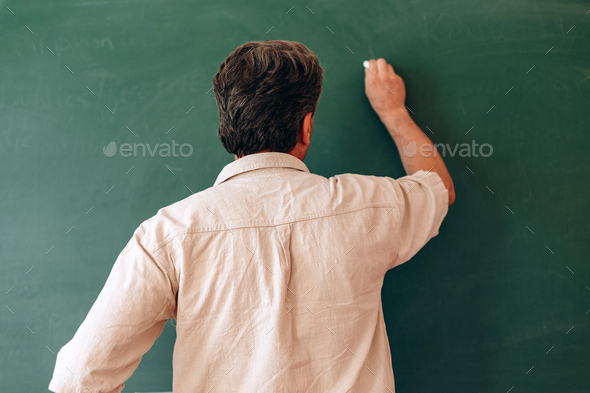 Teacher write on the blackboard and explain a lesson. Back view- Image