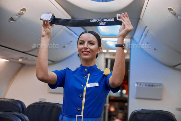 stewardess is showing safety rules before fly at evening plane salon