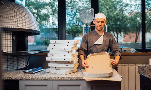 Pizzeria worker building pizza packaging. Catering kitchen work.