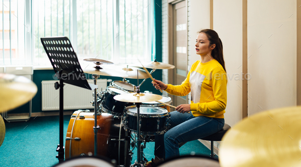 A girl in a music school learns how to play the drums from the notes. Lesson at the music school.