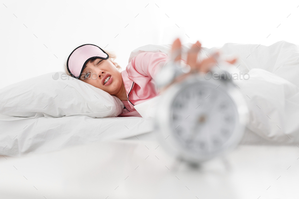 Funny sad tired millennial blonde reaches to alarm clock