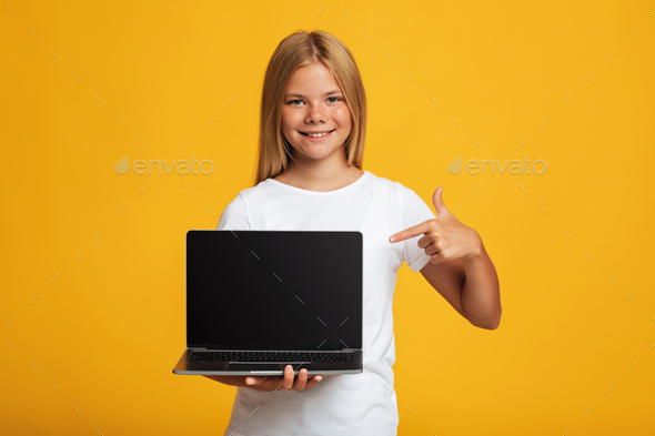 Happy teen female show finger at laptop with empty screen