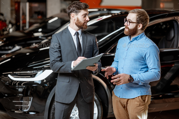 sales-consultant-with-a-client-at-the-car-dealership-stock-photo-by