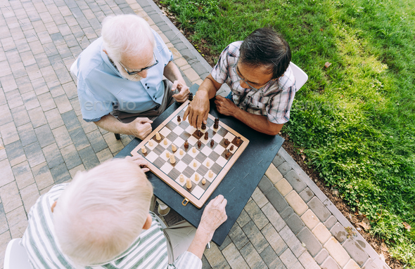 Group of senior friends playing chess at the park