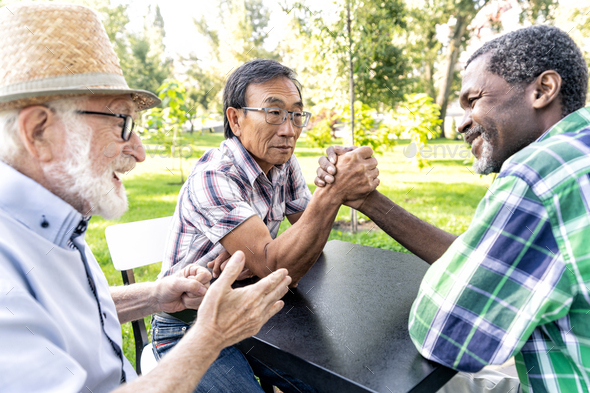 Group of senior friends playing arm wrestling at the park