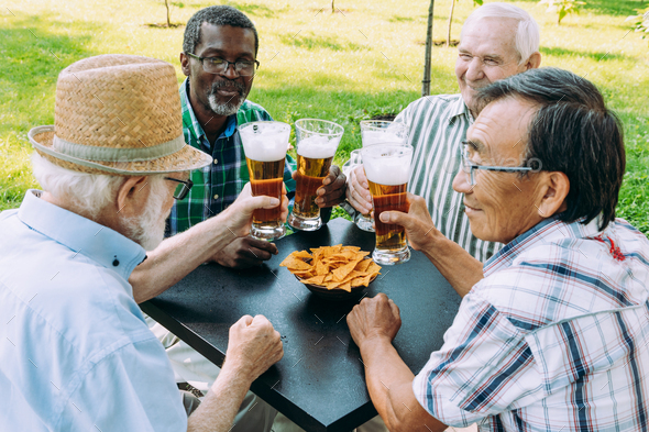 Group of senior friends drinking a beer at the park