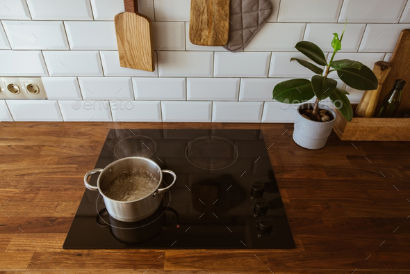 Boiling water in pan. White cooking pot on stove with water and